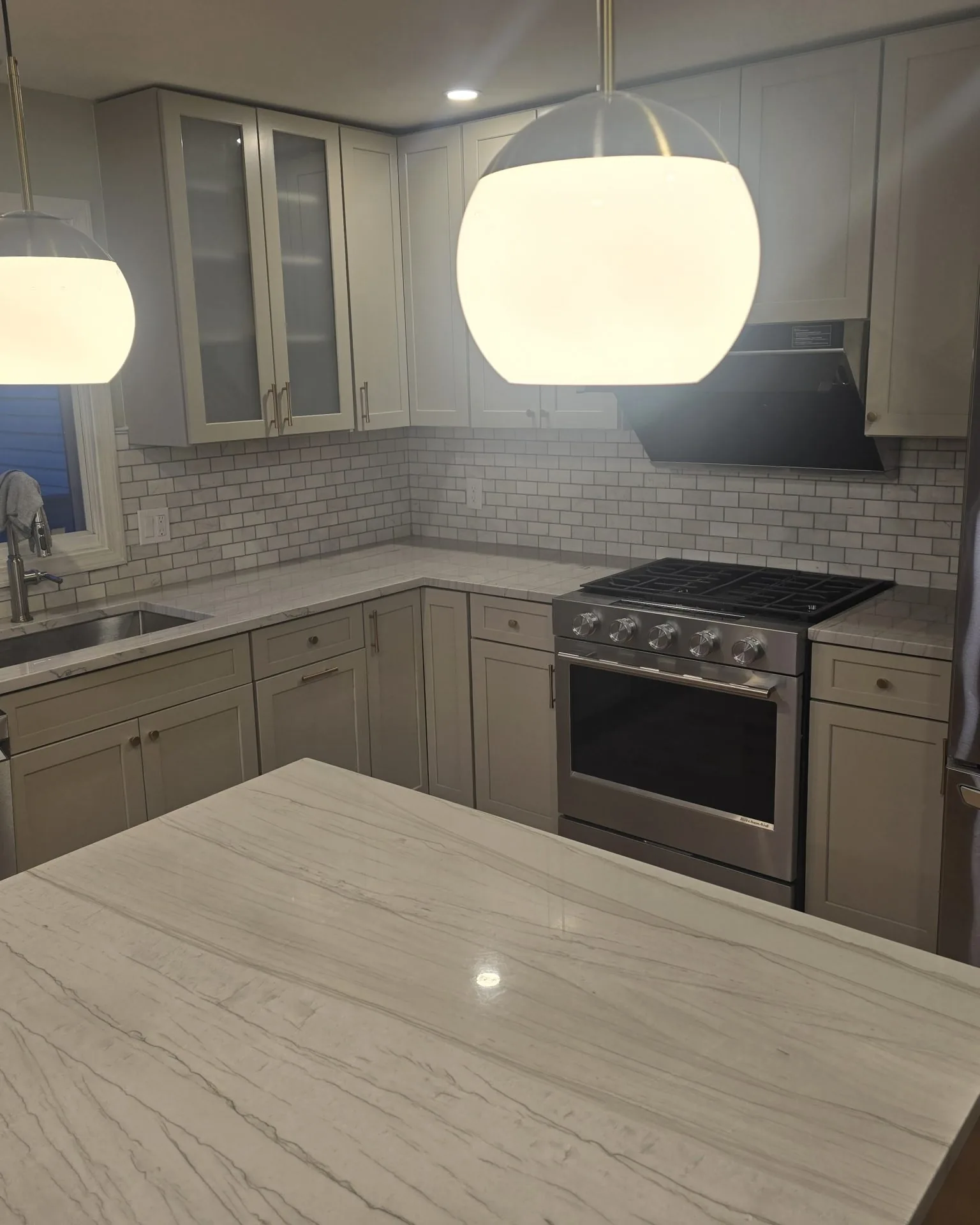 Remodeled kitchen with pendant lighting, tile backsplash, and a stone island