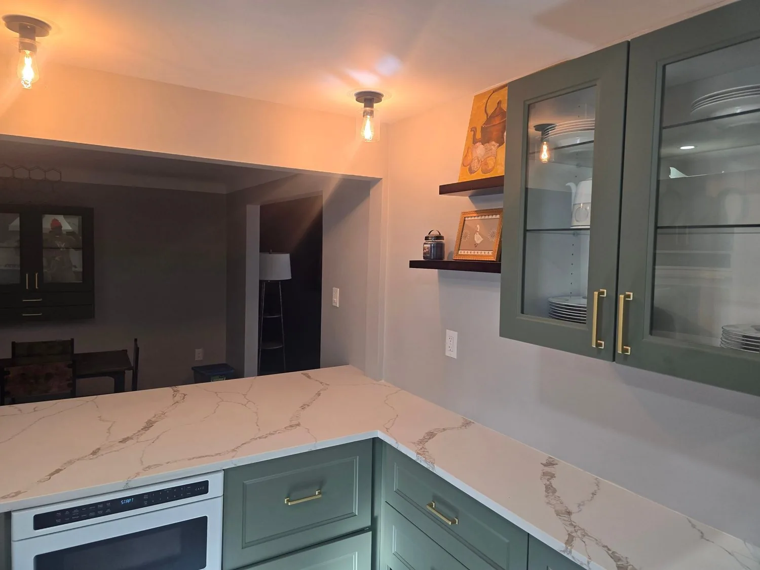 Kitchen with green cabinetry, glass upper doors, and a marble waterfall counter