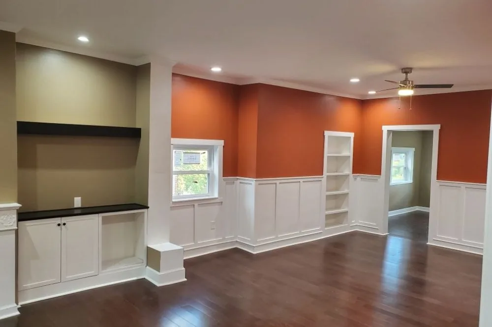 Room with wainscoting, built-in shelving, and a painted accent wall